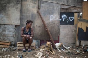 En kvinde sidder med sine hunde i et slumkvarter i udkanten af Rio de Janeiro. 