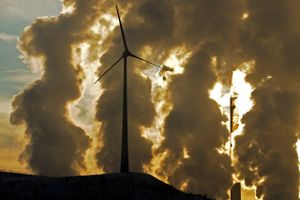 Dampen fra køletårnene ved det kulfyrede kraftværk i tyske Gelsenkirchen danner baggrund for en enlig vindmølle. Foto: AP/Martin Meissner