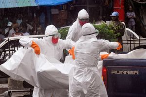 Sundhedsmyndigheder læsser et lig på ladet af en pick-up i en travl og regnfuld gade i Monrovia, Liberia. Afdøde mistænkes for at være smittet med ebola.