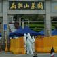 Folk bærer beskyttelsesdragter nær en kirkegård i den kinesiske millionby Wuhan. Det var her, at coronasmitten brød ud i slutningen af 2019. Kina er blevet beskyldt for at dække over omfanget af virusudbruddet i landet og for at underrapportere om både antallet af smittede og døde. Foto: Aly Song/Reuters