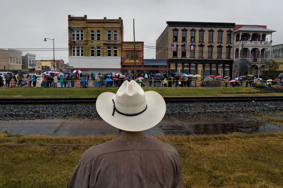 Sgt. Ozell Covington of the Grimes County Sheriff's Office makes sure folks don't get too close to the railroad tracks as they wait for the Bush funeral train in Navasota, Texas. Foto: Washington Post photo by Michael S. Williamson