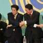 Lederne af flere japanske partier med premierminister Shinzo Abe i midten holder hinanden i hænderne før en politisk debat.
