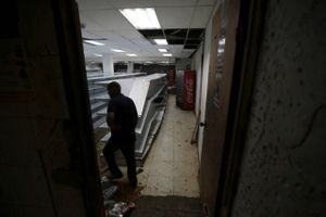 En ansat går forbi tomme hylder i et supermarked i et arbejderkvarter i Caracas, Venezuela, der blev plyndret natten forinden. Foto: AP Foto/Fernando Llano.