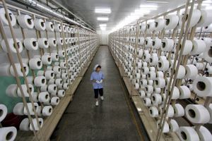 En larbejder vej en tekstilfabrik i Kinas sydlige Fujian provins. Kina er blevet verdens anden største økonomi via sin eksport. Samt vestlige firmaers outsourcing af arbejdspladser til landet. Foto: AP Photo