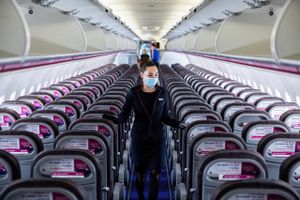 A member of the cabin crew wearing a protective face ask checks cabin seating ahead of the flight on-board a passenger aircraft operated by Wizz Air Holdings at Liszt Ferenc airport in Budapest, Hungary, on May 25, 2020. Foto: Bloomberg/Akos Stiller