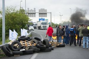 Hundrede af strejkende arbejdere blokerer fredag Calais og bruger blandt andet brændende bildæk for at forhindre adgang til færgerne.