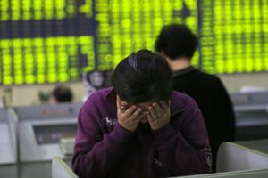 En kvinde gemmer hovedet i hænderne foran en computer terminal med aktieudviklingen i Nantong i det østlige Kinas Jiangsu provins onsdag den 8. juli 2015, hvor Kina's Shanghai Composite Index faldt med 5,9 pct.