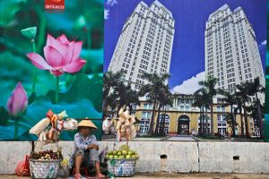 En frugtsælger venter på kunder foran en reklame for et indkøbscenter i Vietnams største by, Ho Chi Minh City. Økonomisk frihed bærer en stor del af æren for »det asiatiske vækstmirakel« i lande som Vietnam, mener udenrigsminister Kristian Jensen (V). Foto: Dita Alangkara/AP