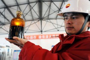 En kineiske arbejder fra China National Petroleum Corporation viser en prøve af den olie, der strømmer fra Rusland til den nordkinesiske storby Daqing. Foto: AP