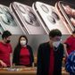Apple staff (red t-shirt) and a customer (R) wearing protective facemasks are seen inside of an Apple store in Beijing on January 30, 2020. - The World Health Organization, which initially downplayed the severity of a disease that has now killed 170 nationwide, warned all governments to be "on alert" as it weighed whether to declare a global health emergency. (Photo by NICOLAS ASFOURI / AFP)