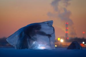 En mand, dækket af plastic for at beskytte sig mod vinden og kulden, borer hul i isen og håber på at fange et par fisk i den finske golf, vest for St. Petersborg.
